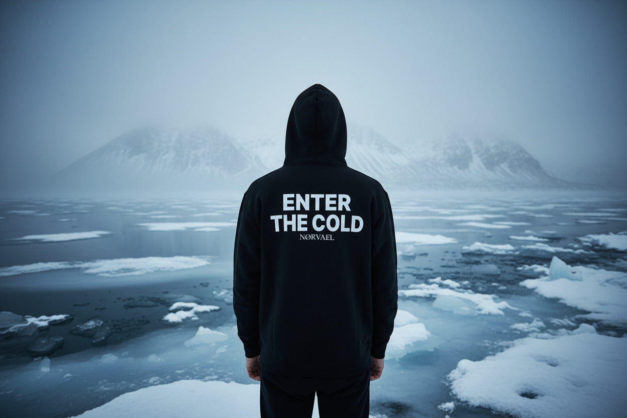 Back view of a black hooded sweatshirt from Nørvael, featuring the "ENTER THE COLD" slogan and brand logo in a bold white print.